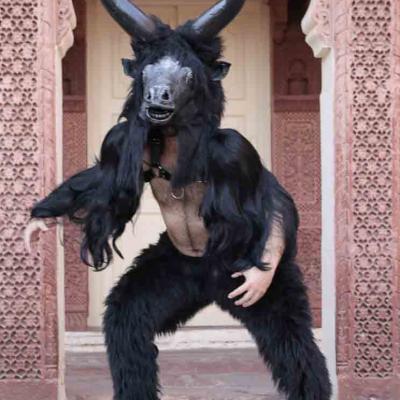 Person in a black horned animal costume posing in front of an ornate stone doorway.